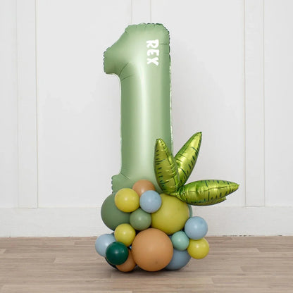 Green balloon number 1 with 'REX' text and colorful dinosaur-themed balloon cluster on wooden floor