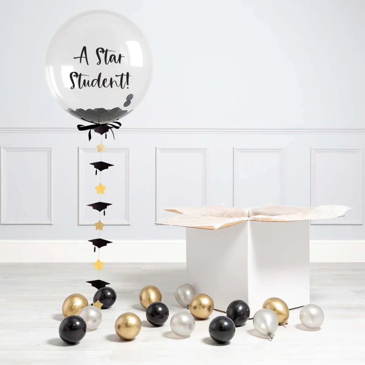 Clear graduation balloon with 'A Star Student!' text, black confetti, stars, caps, and gold, black, silver balloons