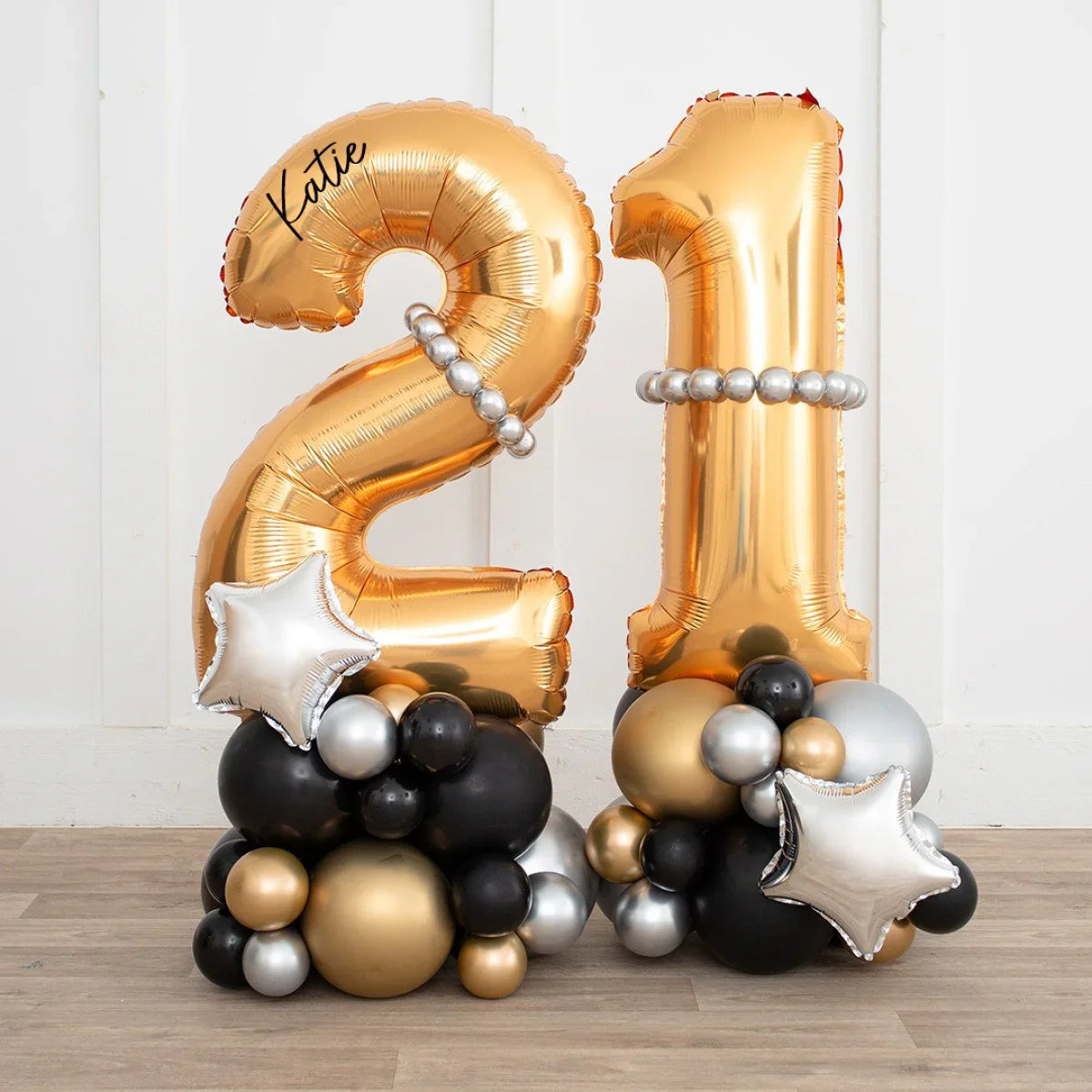Personalized gold number 21 balloons with silver bead garlands and black, gold, silver balloon base with silver star balloons