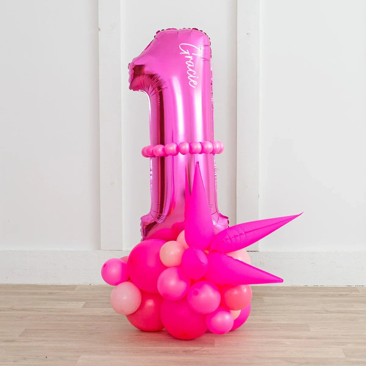 Personalized neon pink number 1 balloon stack with name Gracie and pink balloon cluster