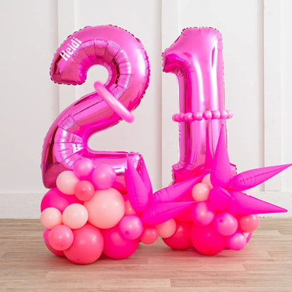 Personalized neon pink foil number 21 balloons with pink balloon clusters on wooden floor