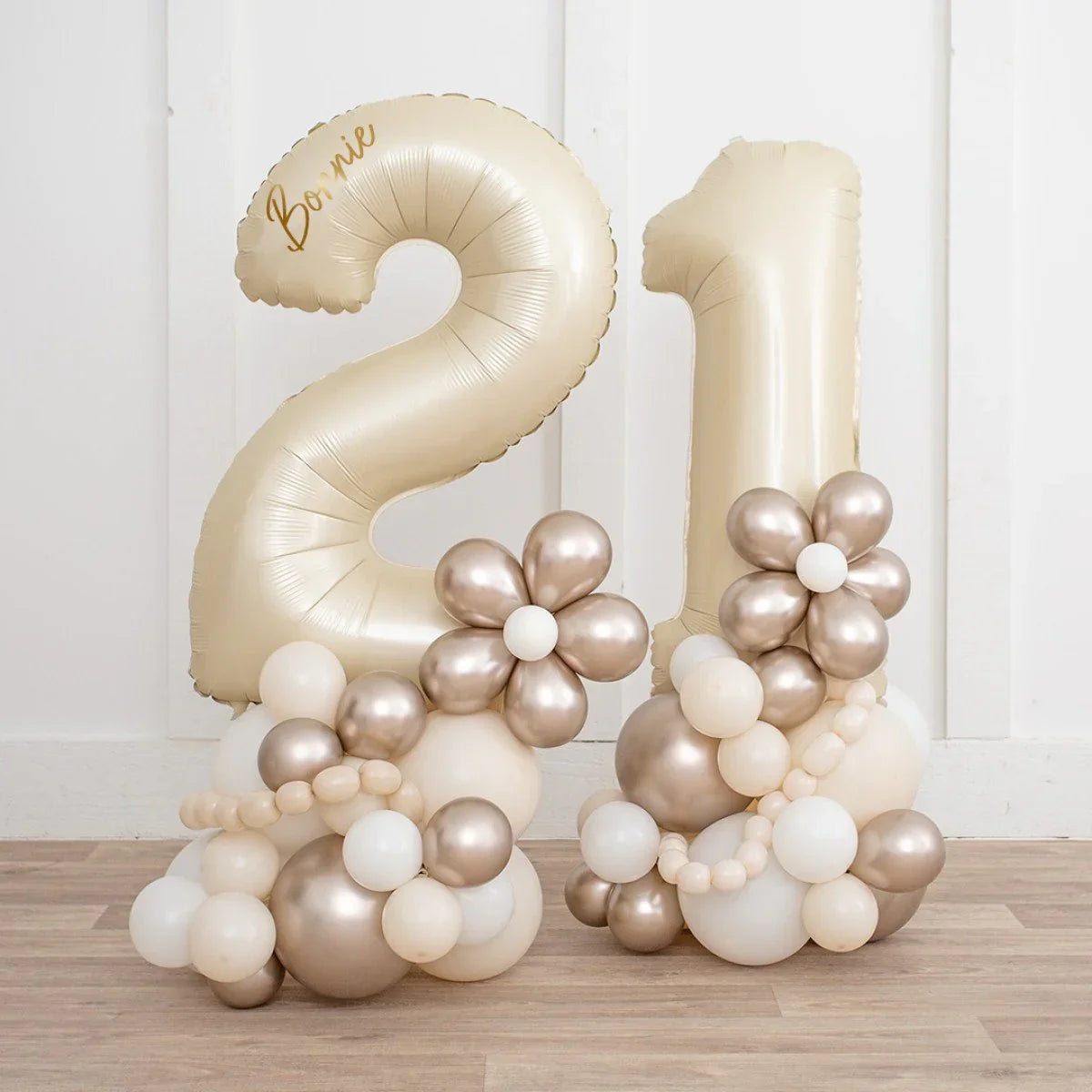 Pearl gold number 21 balloons with metallic floral decorations on wooden floor