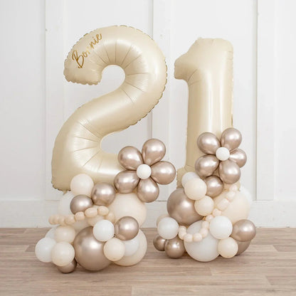 Pearl gold number 21 balloons with metallic floral decorations on wooden floor