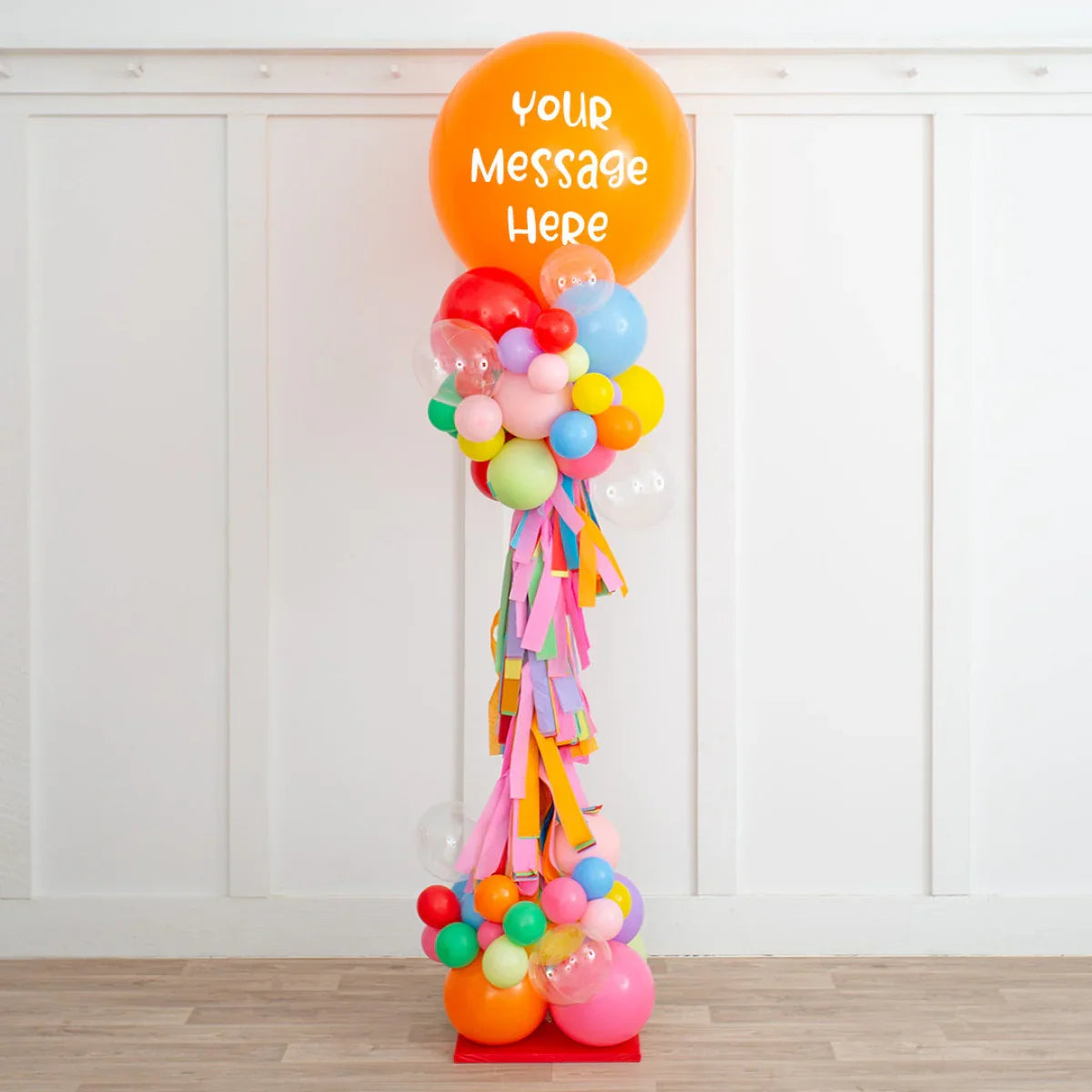 Colorful personalized balloon pillar with large orange balloon and multicolor bubbles