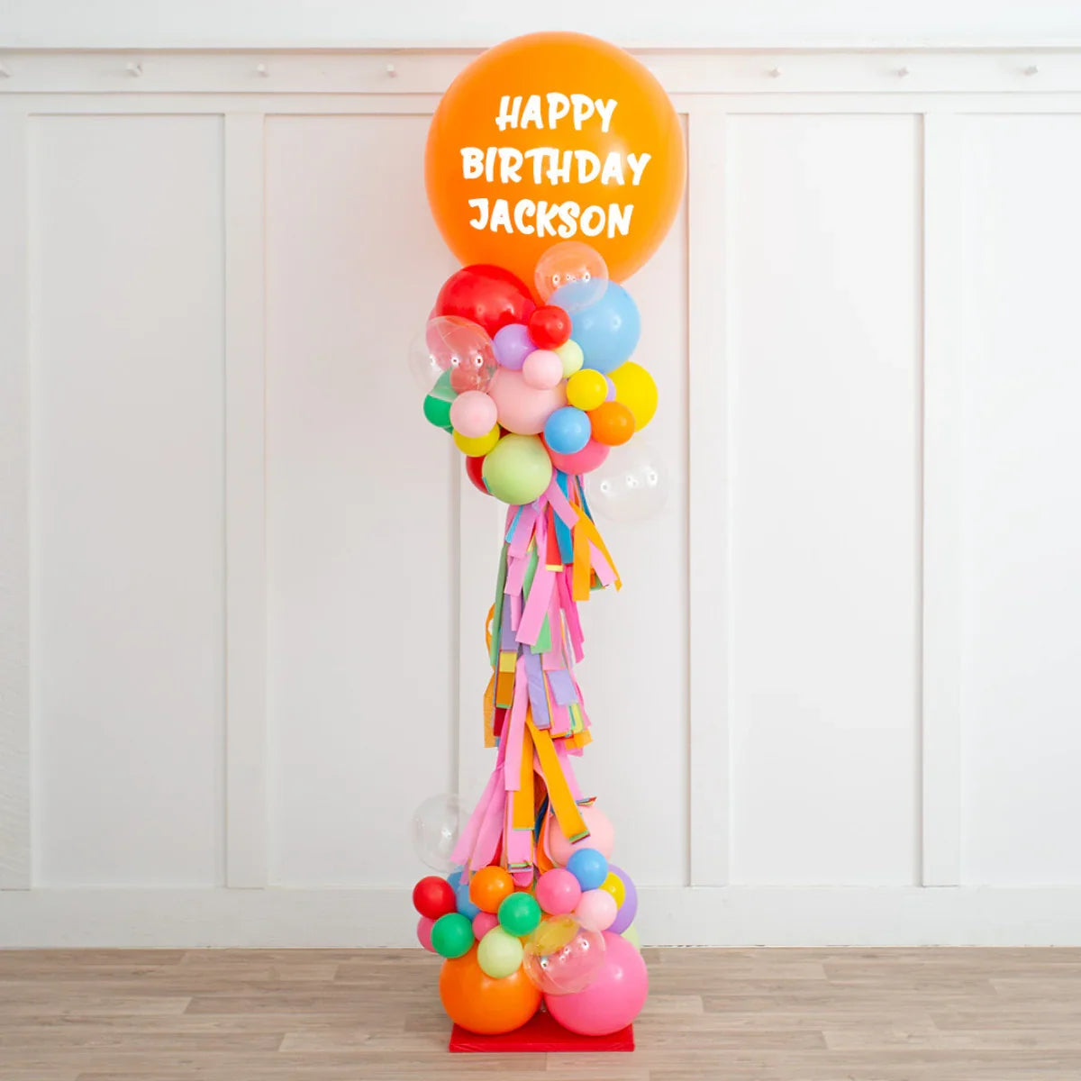 Tall colorful balloon pillar with personalized Happy Birthday Jackson message on large orange balloon