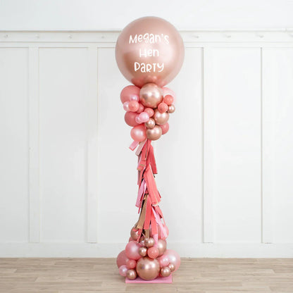 Rose gold and blush balloon pillar with personalized text Megan's Hen Party in a white room