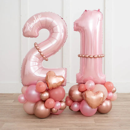 Personalized rose gold 21 number balloons with blush and metallic balloon clusters on wooden floor
