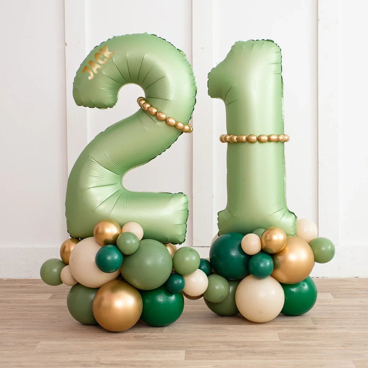 Personalized forest green inflated number balloons 2 and 1 with gold and green balloon clusters on wooden floor