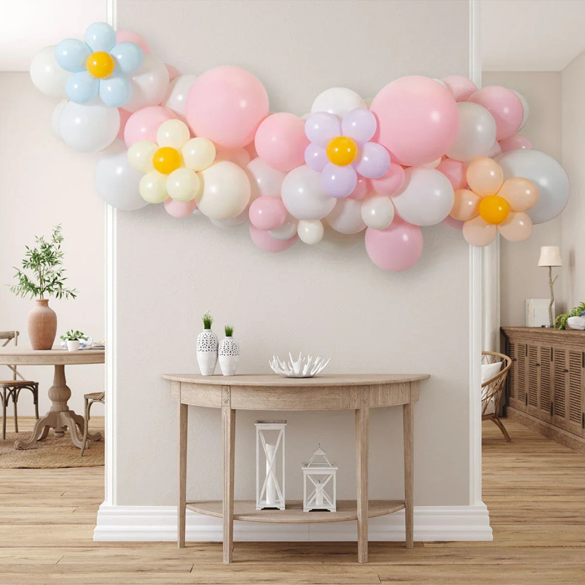 Pink pastel and white balloon garland with colorful daisy-shaped balloons above wooden console table