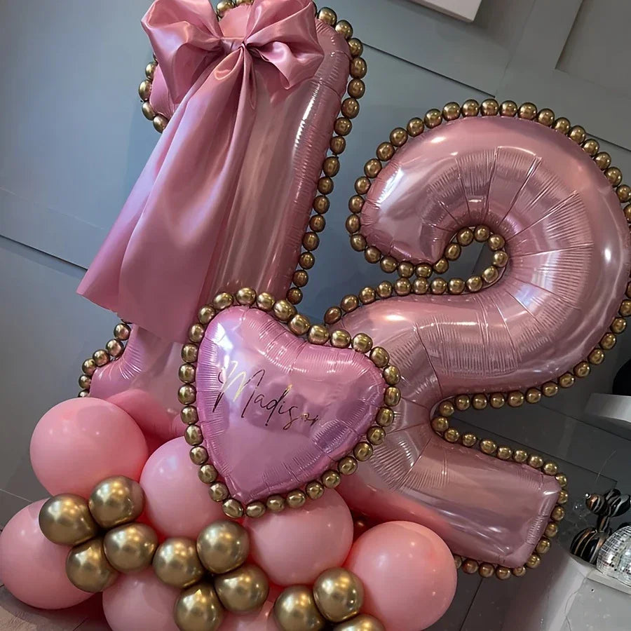 Pink and gold number 12 balloon arrangement with pink bow and heart-shaped balloon reading Madison