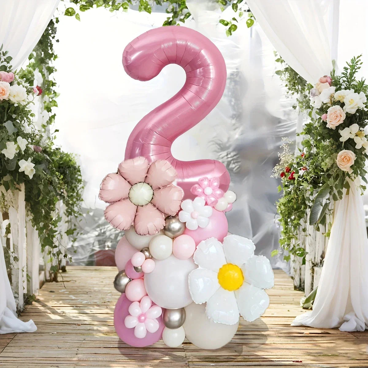 Pink number 2 balloon decoration with flower-shaped balloons in floral archway setting on wooden floor
