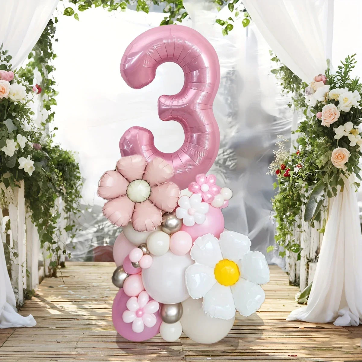 Pink number 3 balloon centerpiece with flower-shaped balloons, set on wooden deck with floral arch