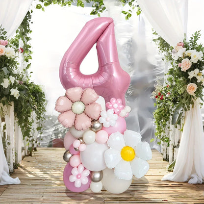 Pink number 4 balloon bouquet with flower-shaped balloons on wooden floor decorated with white drapes and greenery