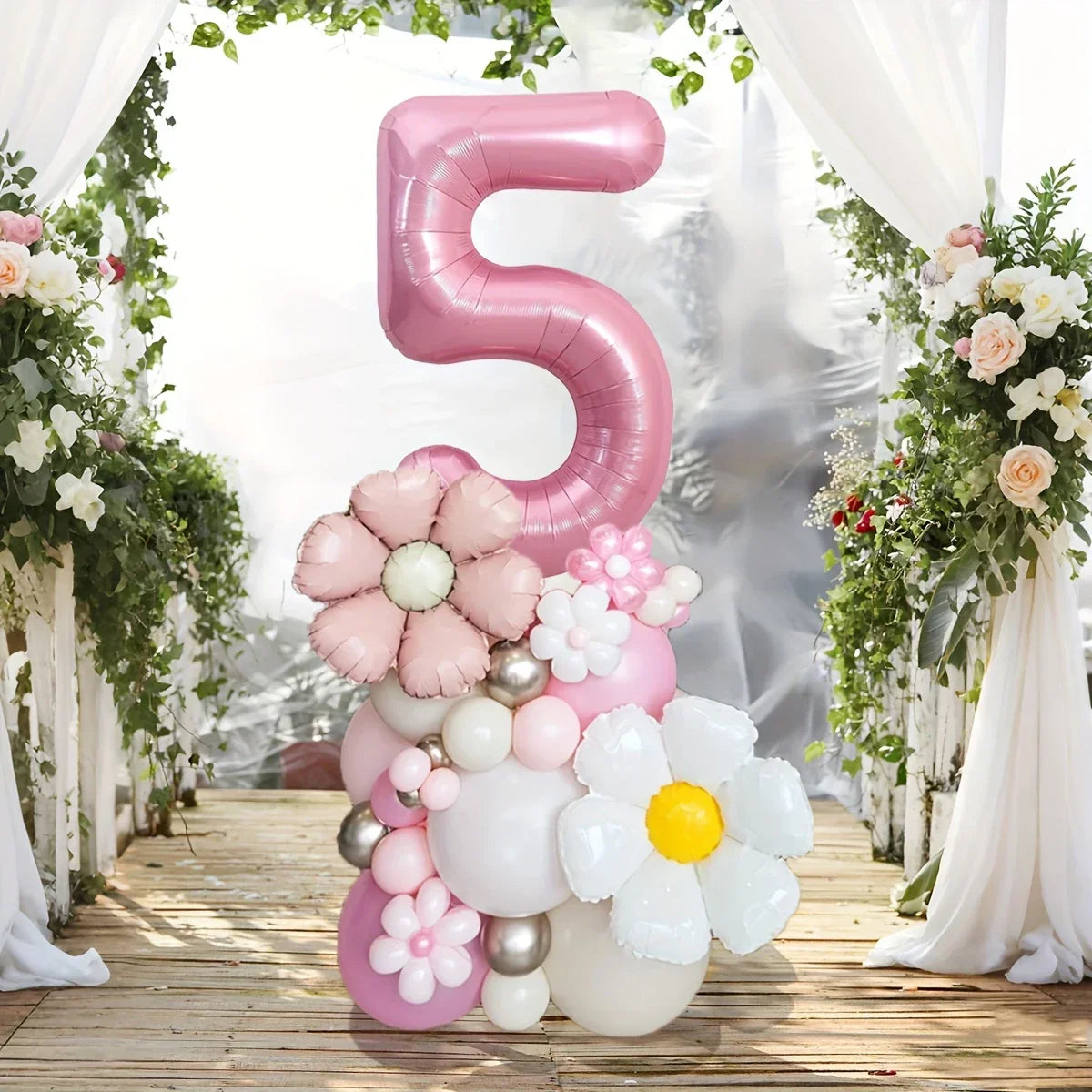 Pink number 5 balloon with floral and pastel balloon bouquet on wooden floor under white draped arch