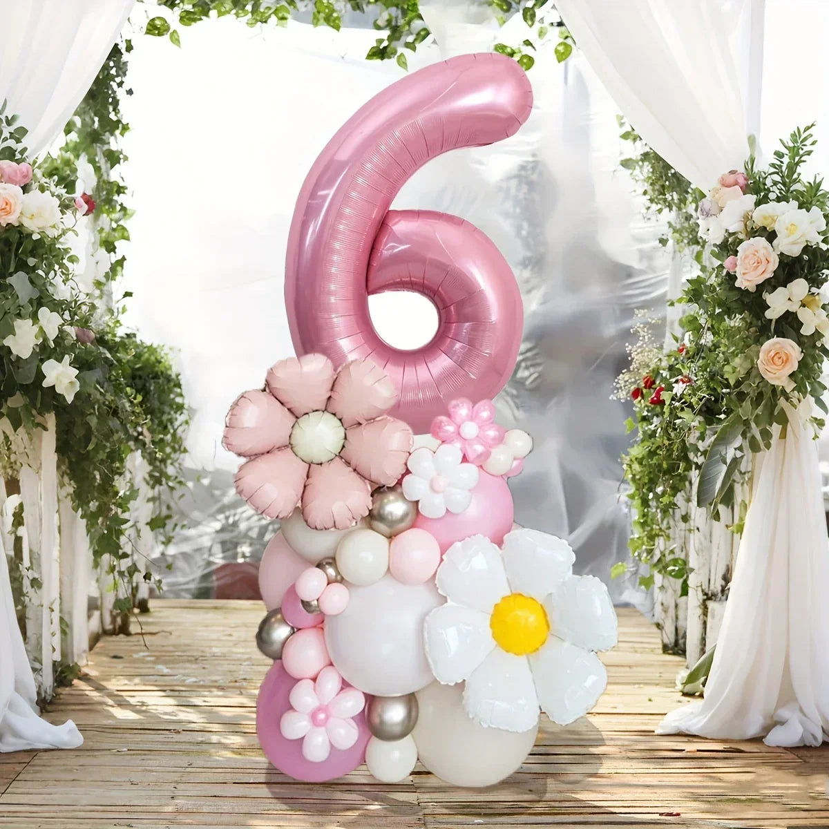 Pink number 6 balloon arrangement with flower-shaped balloons on wooden floor with floral arch