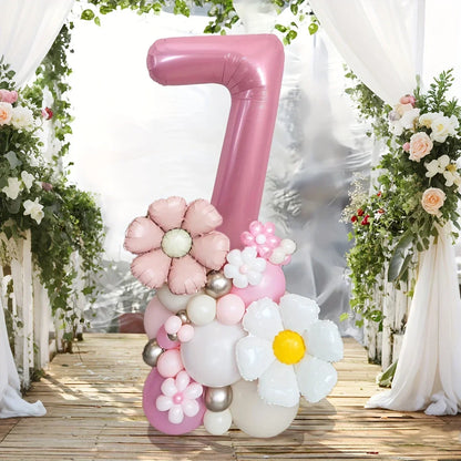 Pink number 7 balloon decoration with floral balloon accents on wooden floor with white drapes and greenery