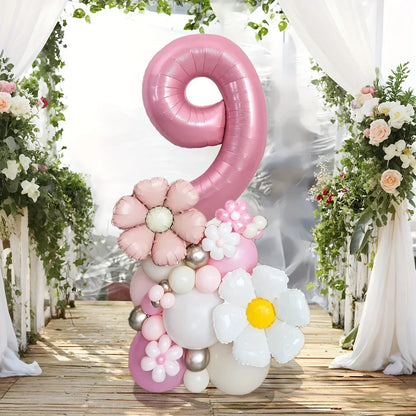 Pink number 9 balloon decoration with floral balloons, set on wooden floor with white drapes and greenery