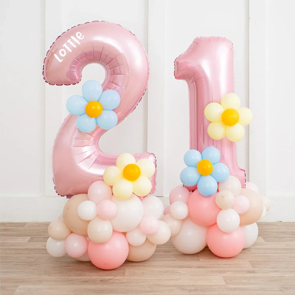 Pink pastel number 21 balloon stack with blue and yellow daisy balloons on wooden floor