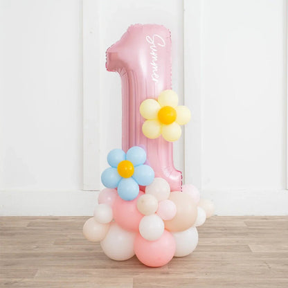 Pink number 1 balloon with pastel balloon flowers and clusters on wooden floor against white wall