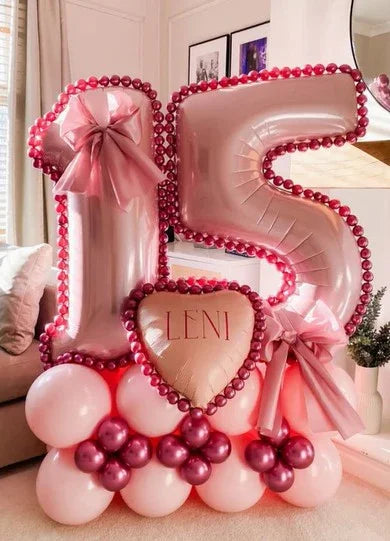 Pink and red balloon arrangement with number 15 and heart-shaped balloon reading Leni, decorated with ribbons