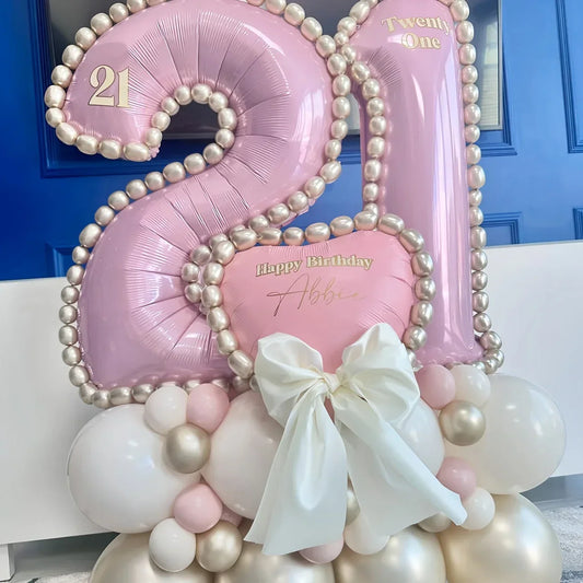 Pink and white metallic 21 birthday balloon arrangement with pearl accents and large white bow
