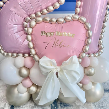 Pink heart-shaped birthday balloon with white bow and metallic pearl balloons in pastel pink and white