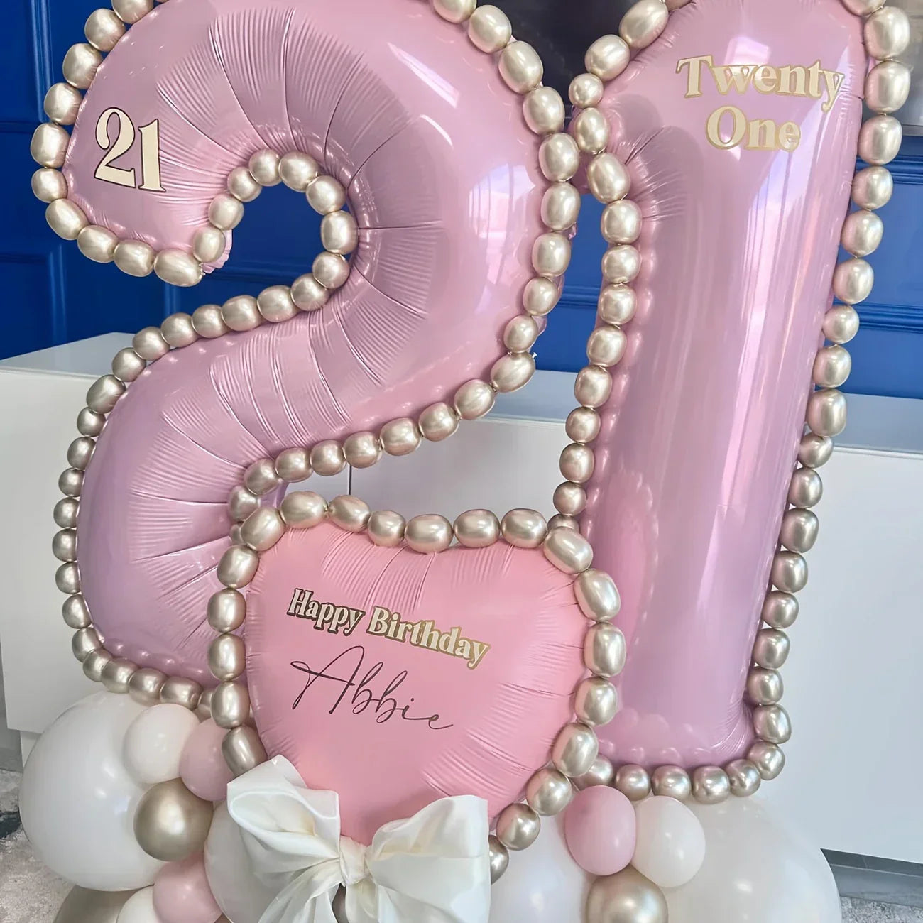 Pink metallic 21 number balloons decorated with pearl beads and white bow for birthday celebration