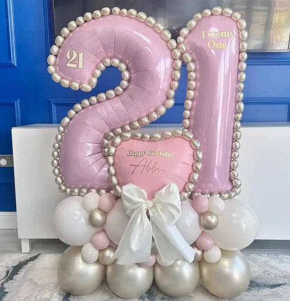 Pink and white metallic 21 number balloon stack with pearl trim and Happy Birthday Abbie message, decorated with white bow