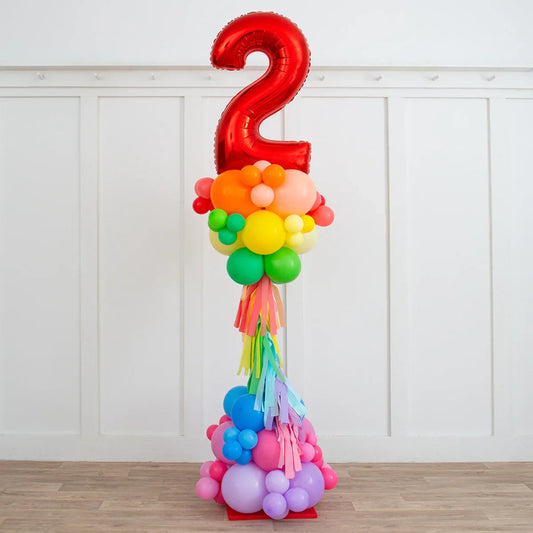 Colorful balloon pillar with large red number 2 balloon and rainbow fringe in a white room
