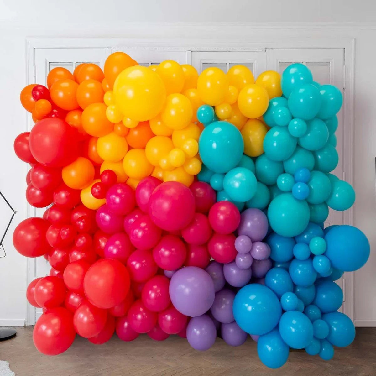 Colorful balloon wall decoration in red, orange, yellow, pink, purple, and blue tones indoors