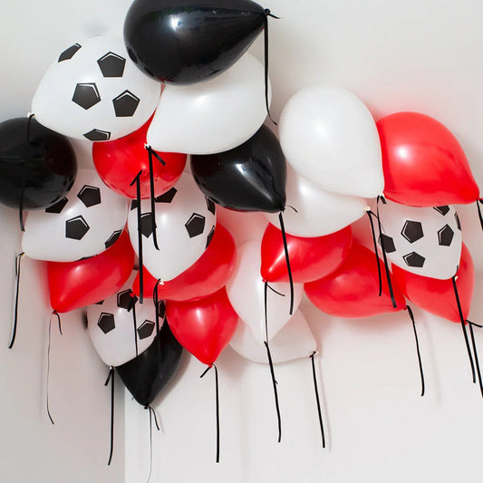 Cluster of red, white, and black helium balloons with soccer ball print floating on a ceiling