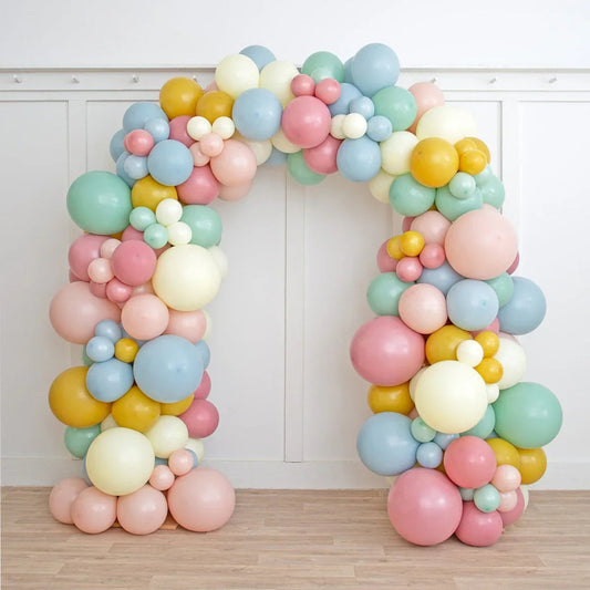 Retro pastel balloon arch with yellow, pink, blue, and green balloons in indoor setting