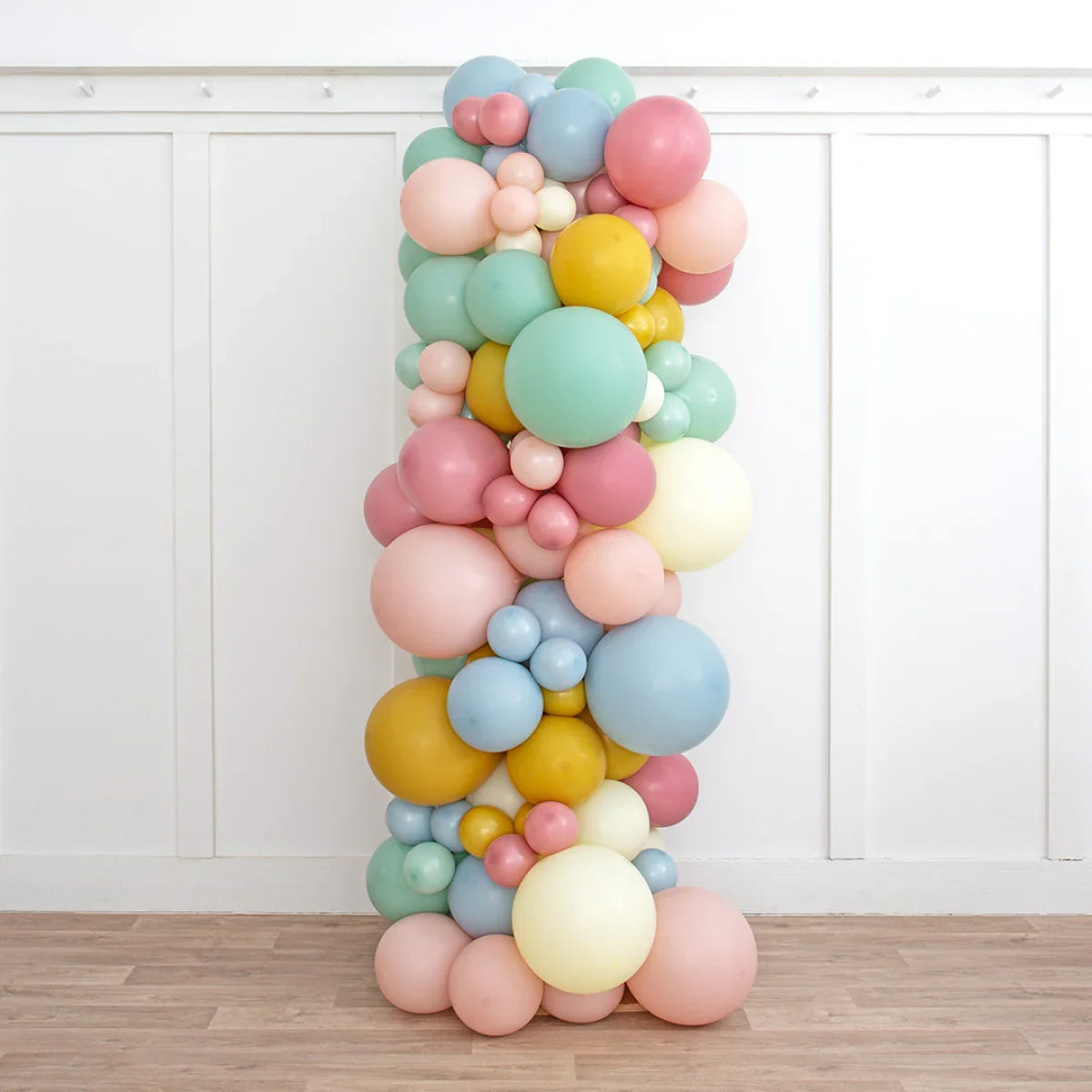 Retro pastel balloon pillar with pink, yellow, blue, and mint balloons in white room