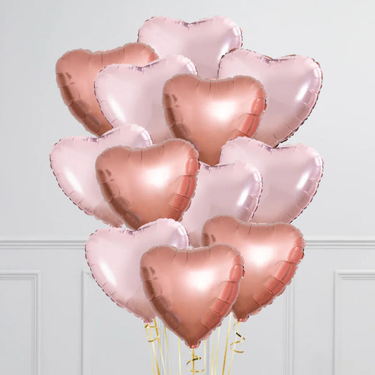 Cluster of rose gold and light pink heart-shaped foil balloons against white wall
