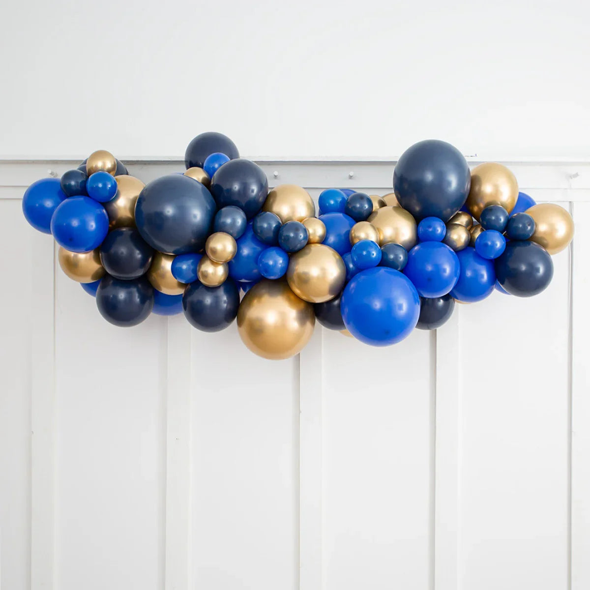 Blue, navy, and gold inflated balloon garland hanging against white paneled wall