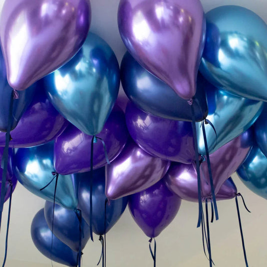 Cluster of shiny blue and purple helium balloons tied with black ribbons against a ceiling