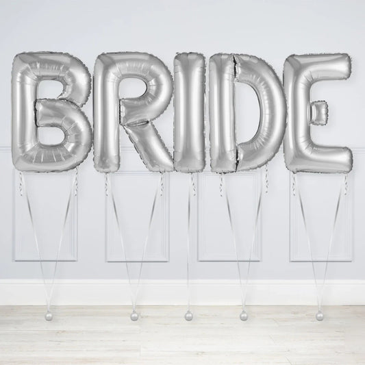 Silver inflated balloons spelling BRIDE against a white wall and wooden floor