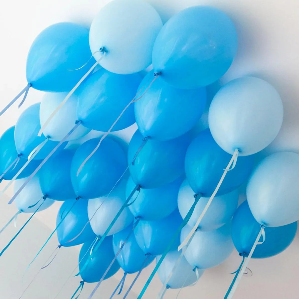 Cluster of sky blue and light blue helium balloons attached to ceiling with matching ribbons