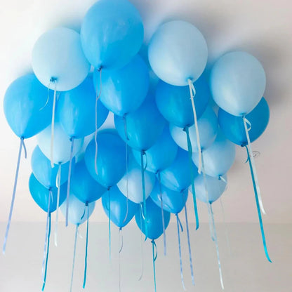 Cluster of light and dark blue helium balloons tied with ribbons floating on a white ceiling