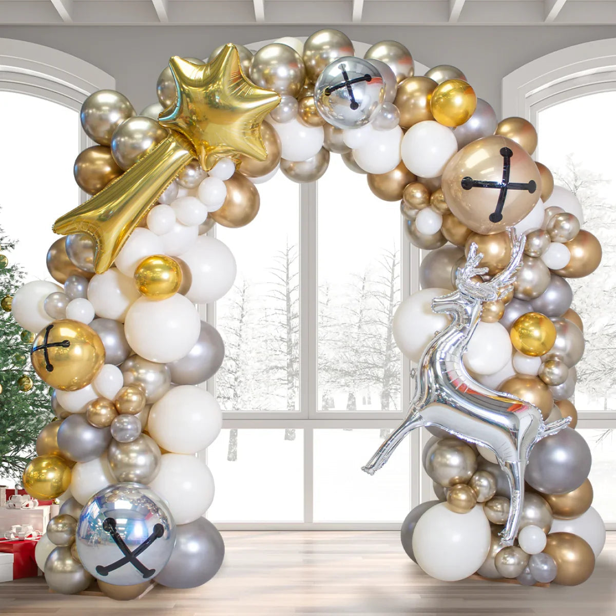 Festive balloon arch with gold, silver, white balloons, featuring star, jingle bell, and reindeer shapes in a bright room