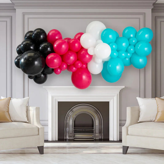 Colorful balloon garland in black, red, white, and turquoise over white fireplace in elegant living room