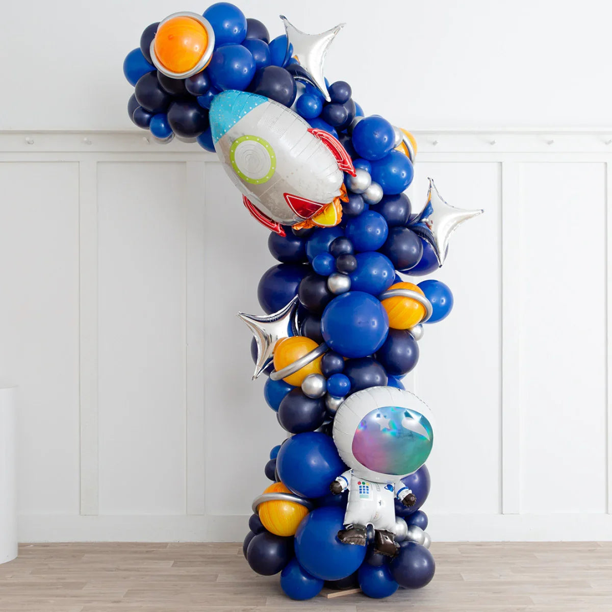 Space-themed balloon arch with blue, silver, orange planet balloons, rocket and astronaut foil balloons