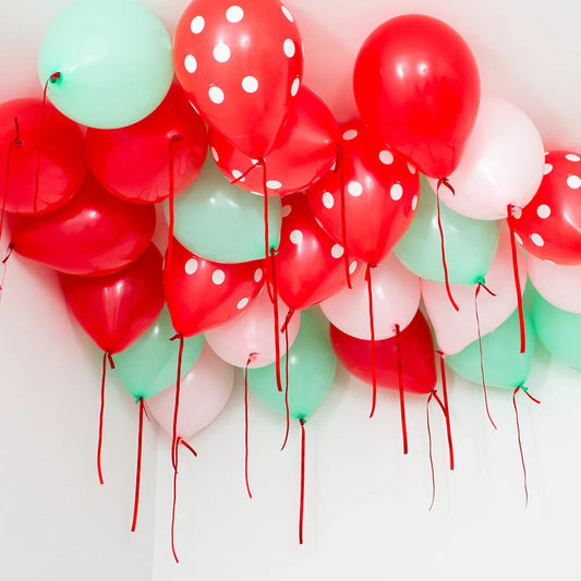 Cluster of red, mint green, and pink helium ceiling balloons with red ribbons, some red balloons have white polka dots
