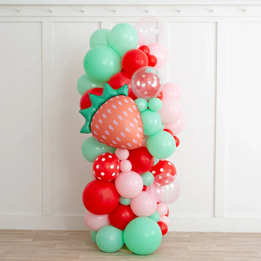 Colorful balloon pillar with strawberry foil balloon and red, pink, green, and polka dot latex balloons