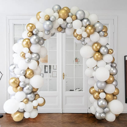 Decorative balloon arch in white, gold, and silver metallic colors set indoors by white double doors