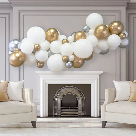 Metallic balloon garland in gold, silver, and white above white fireplace in elegant living room