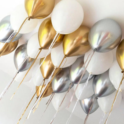 Cluster of metallic gold, silver, and white helium balloons tied with ribbons on ceiling