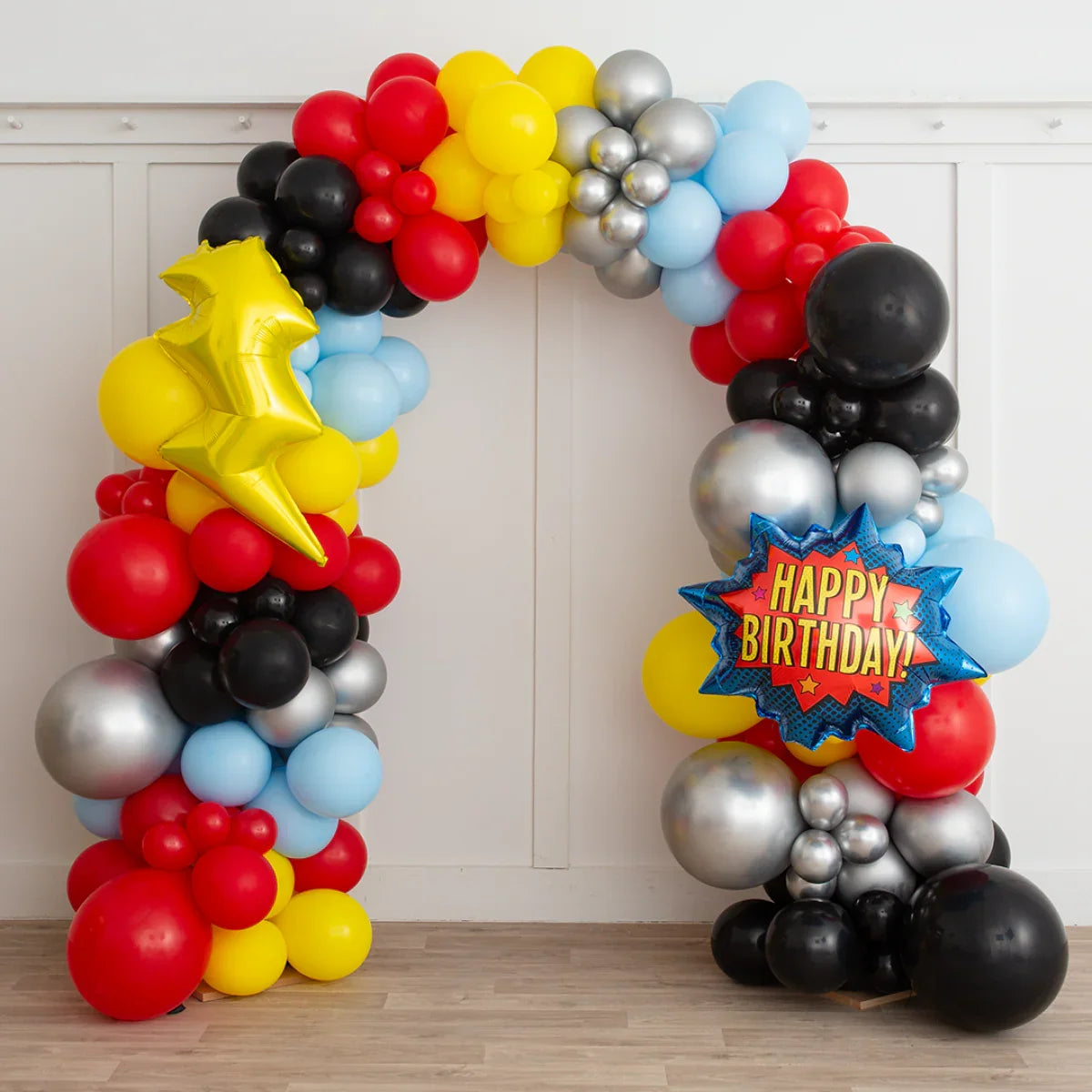 Colorful birthday balloon arch with red, yellow, black, blue, silver balloons and happy birthday star balloon