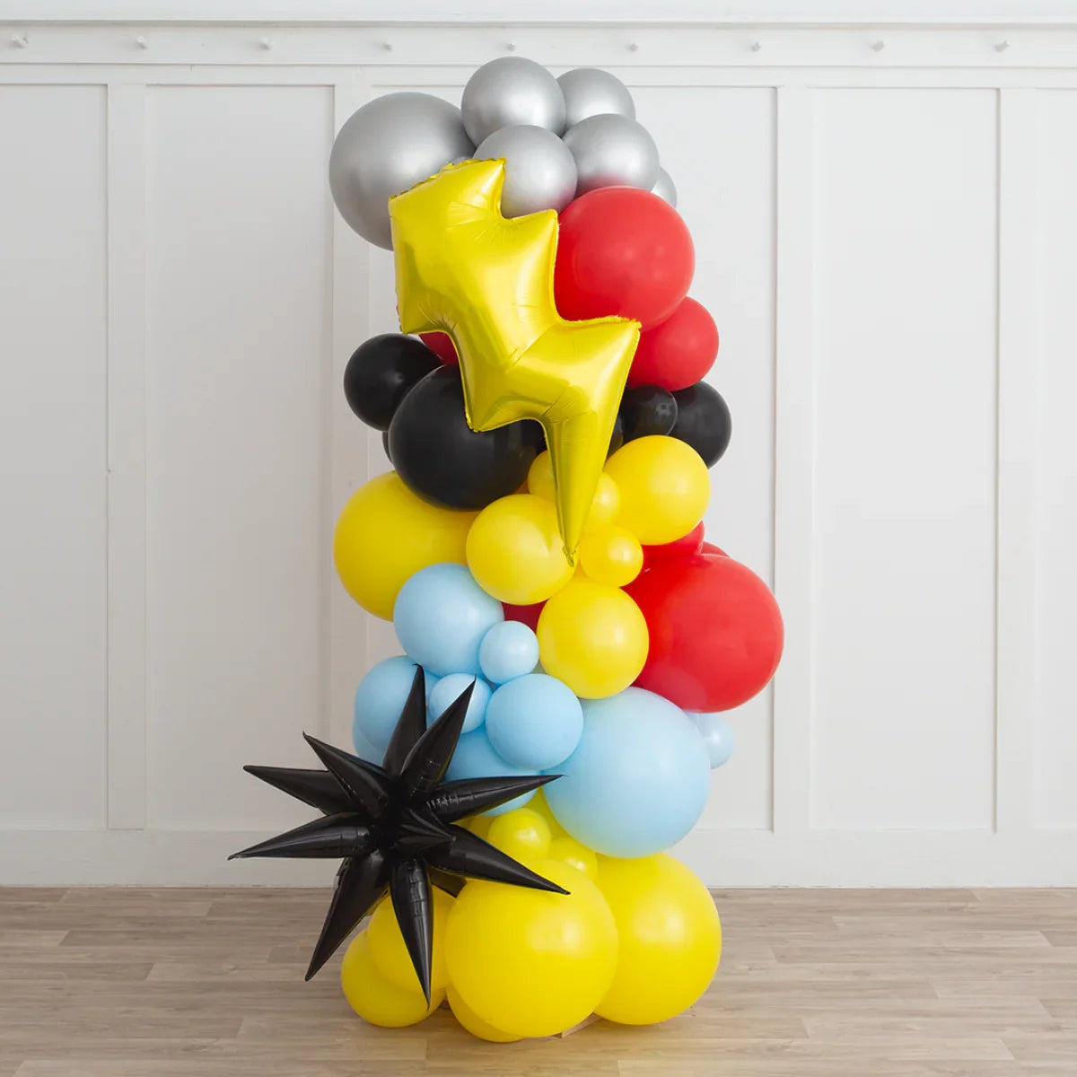 Colorful superhero-themed balloon pillar with yellow lightning bolt and black star accents indoors
