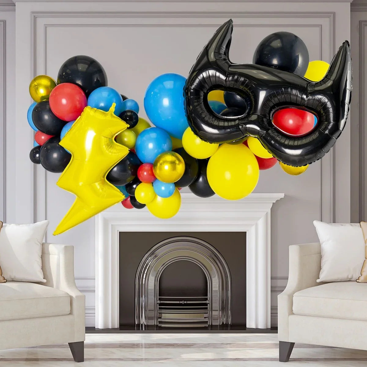 Superhero-themed balloon garland with black mask and yellow lightning bolt over white fireplace in living room